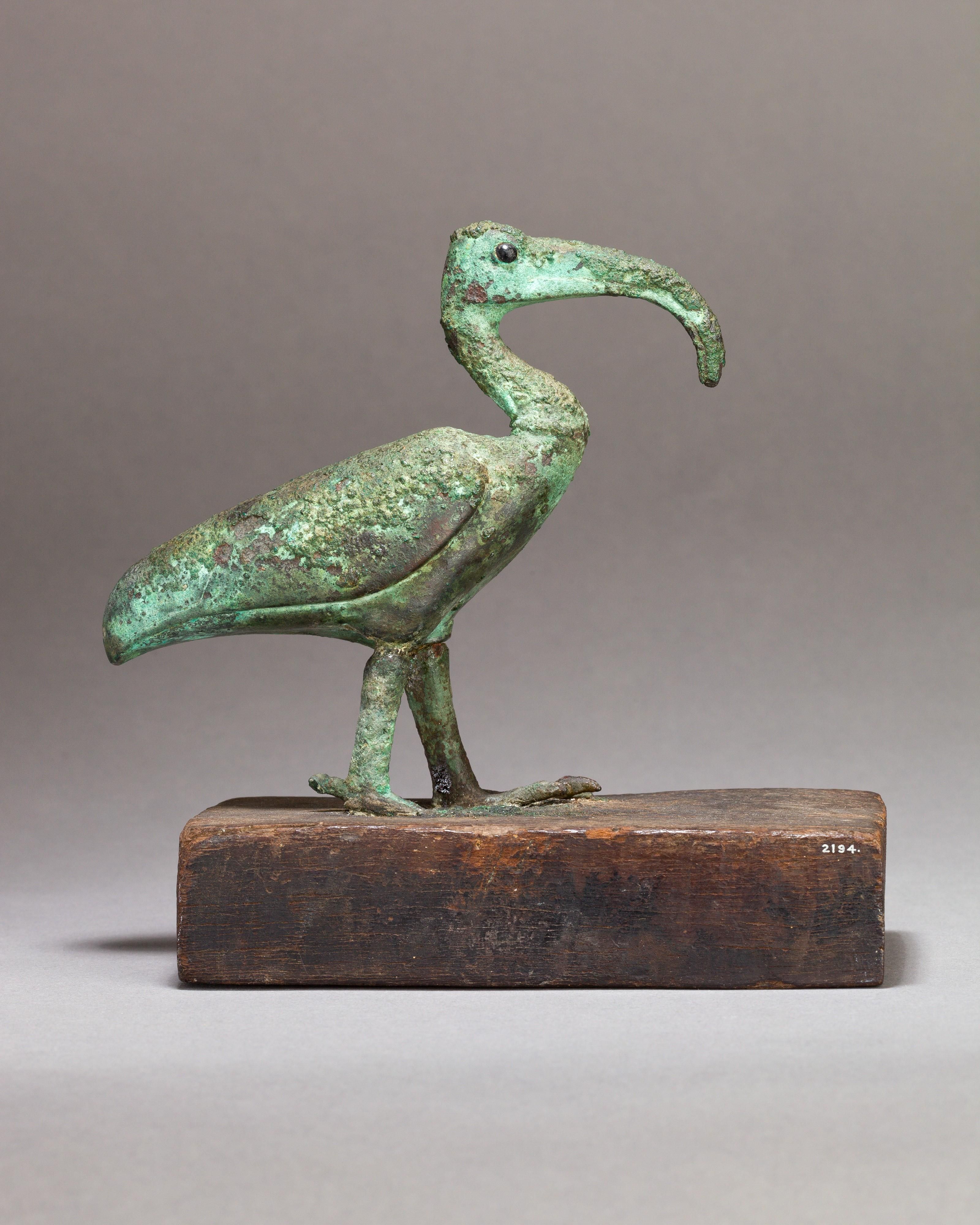 A metal figure showing a bird on a wooden base