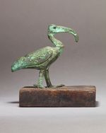 A metal figure showing a bird on a wooden base