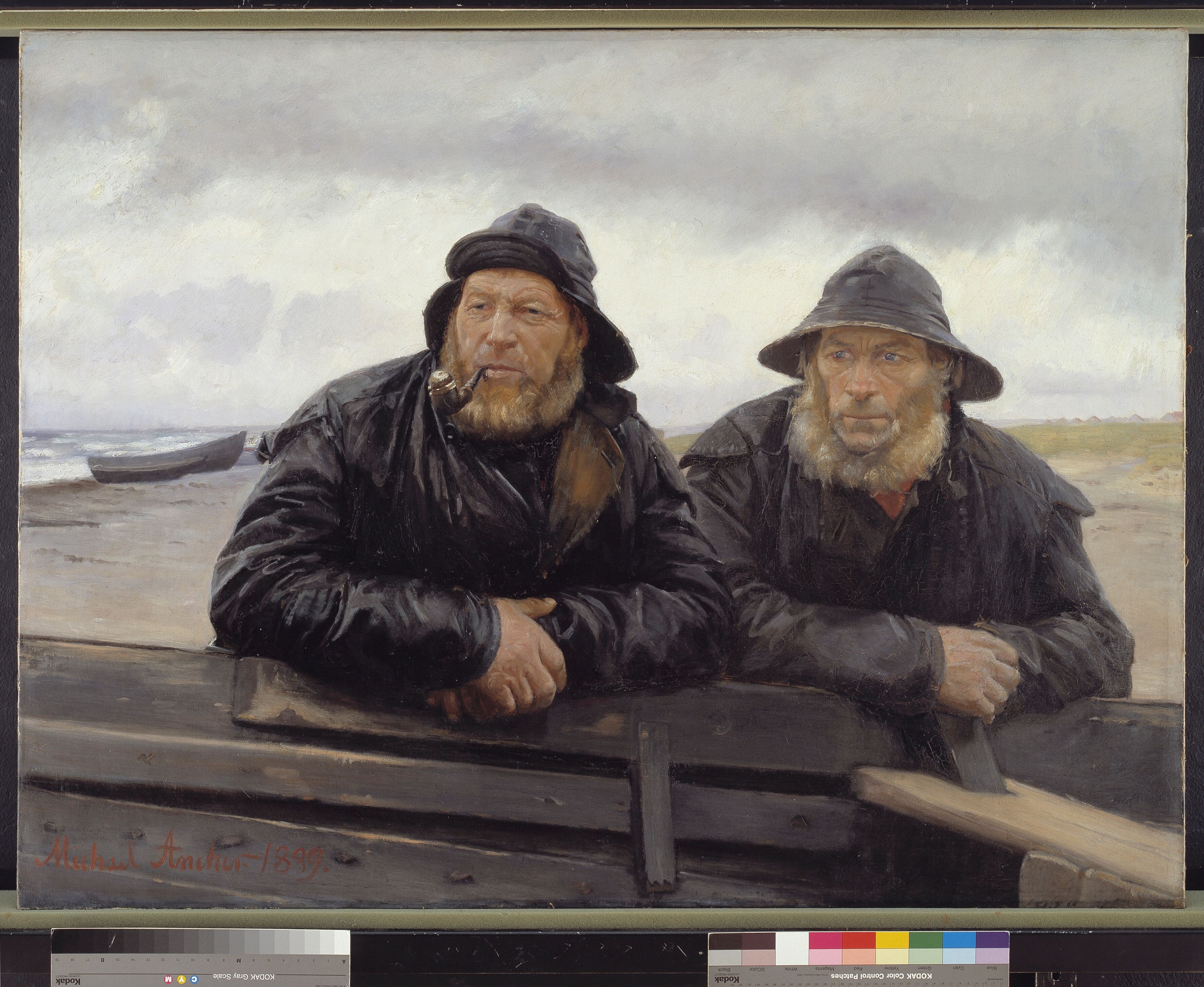 Two bearded men in black rain coats and rain caps lean against the edge of a wooden fishing boat lying on the beach and look thoughtfully into the distance