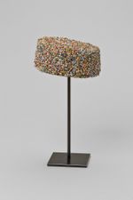 A decorative colorful cap displayed on a black metal stand